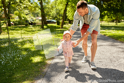 Image of happy father with baby daughter walking at park