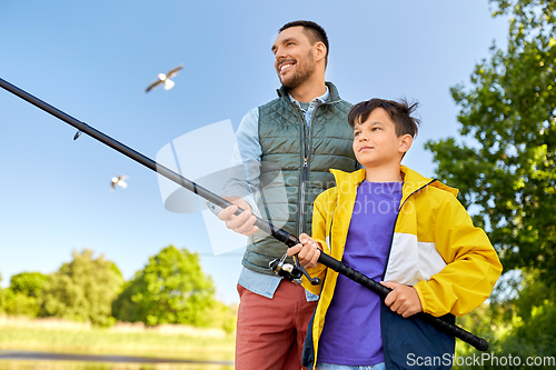 Image of happy smiling father and son fishing on river