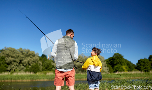 Image of happy smiling father and son fishing on river