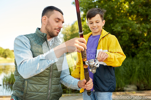 Image of happy smiling father and son fishing on river