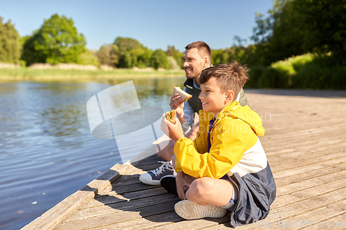Image of father and son eating sandwiches on river berth