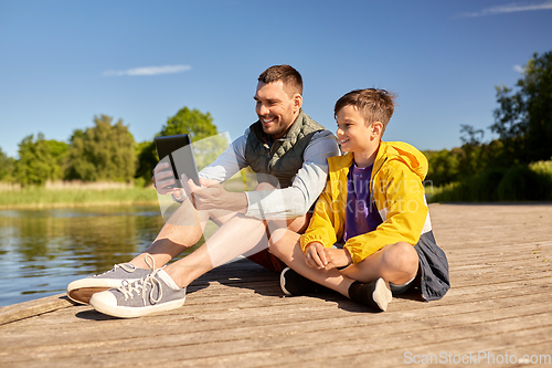 Image of happy father and son with tablet pc on river berth