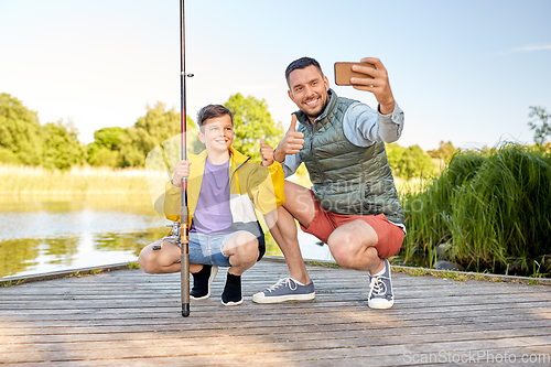 Image of father and son with fishing rods taking selfie