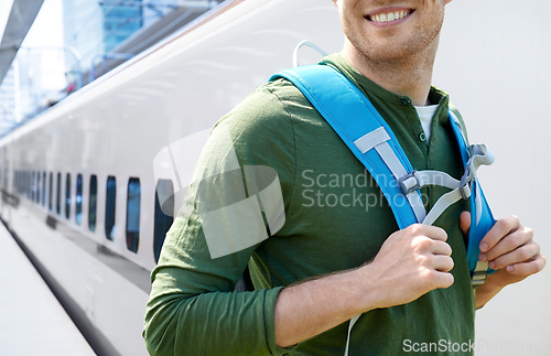 Image of smiling man with backpack traveling over train