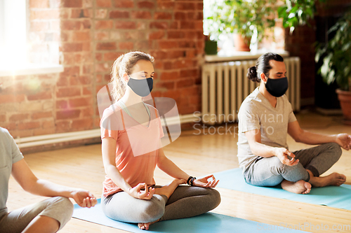 Image of group of people in masks meditating at yoga studio