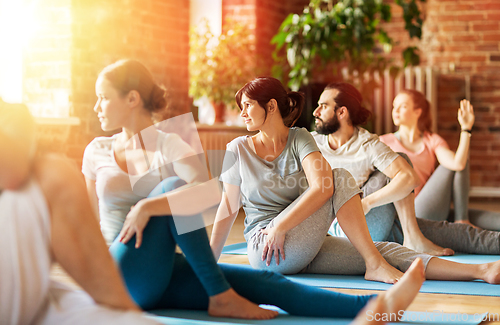 Image of group of people doing yoga exercises at studio