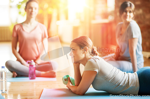 Image of group of women resting on yoga mats at studio