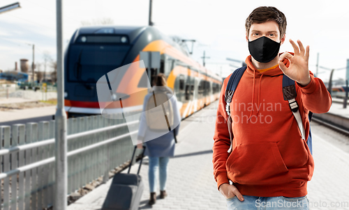 Image of man in mask with backpack traveling by train