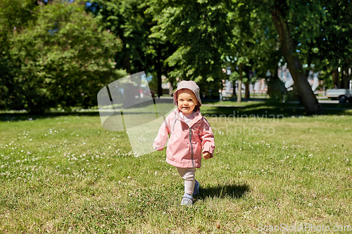 Image of happy little baby girl walking in summer park