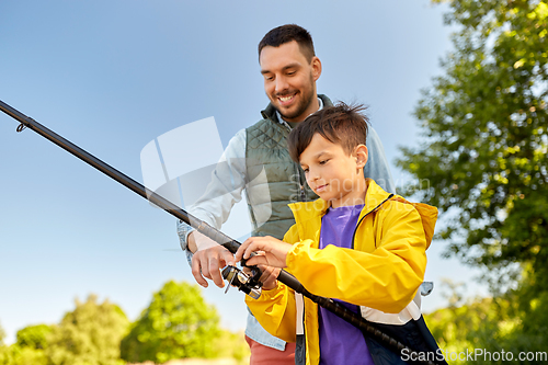 Image of happy smiling father and son fishing on river