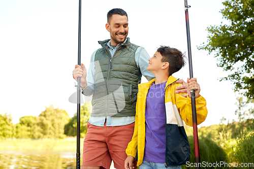 Image of happy smiling father and son fishing on river