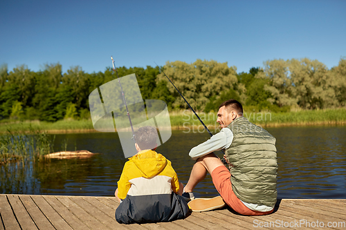 Image of happy smiling father and son fishing on river