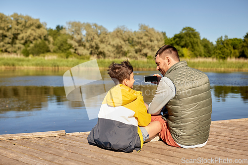 Image of father and son taking selfie with phone on river