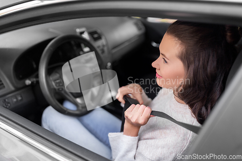 Image of woman or female car driver fastening seat belt