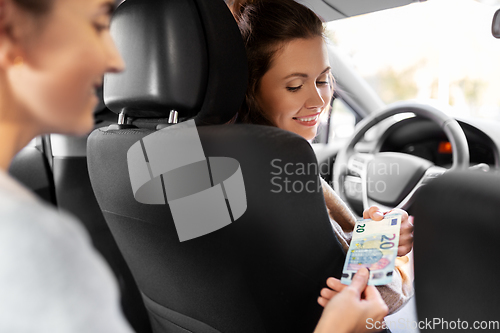 Image of female car driver taking money from passenger