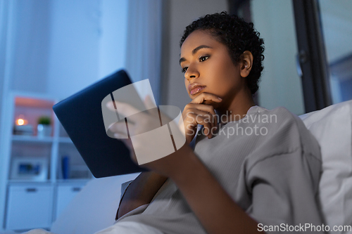 Image of woman with tablet pc in bed at home at night