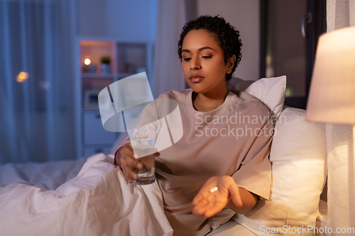 Image of woman with medicine and water in bed at night