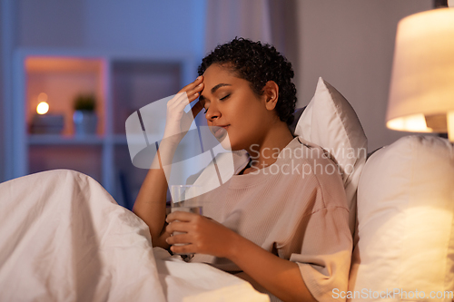 Image of stressed african woman lying in bed at night