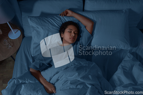 Image of african woman sleeping in bed at home at night