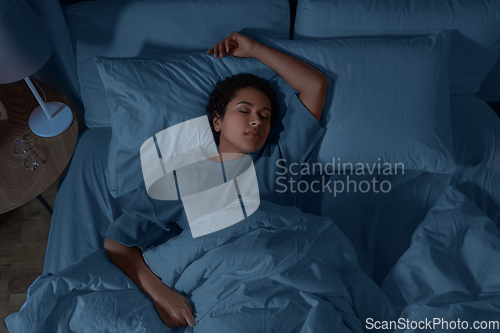 Image of african woman sleeping in bed at home at night