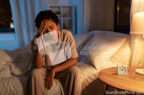 Image of stressed african woman lying in bed at night