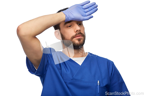 Image of tired doctor or male nurse in blue uniform