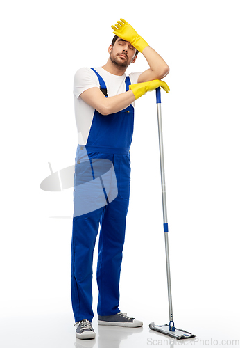 Image of tired male cleaner cleaning floor with mop