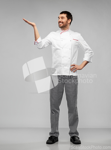 Image of happy smiling male chef holding something on hand
