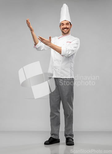 Image of happy smiling male chef showing something