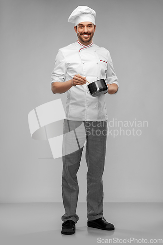 Image of happy smiling male chef with saucepan cooking food