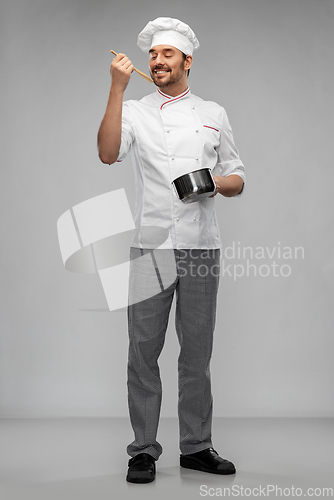 Image of happy smiling male chef with saucepan tasting food