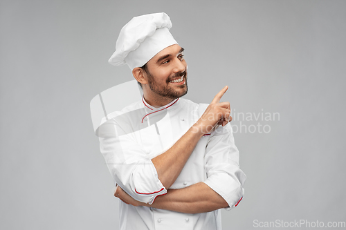 Image of happy smiling male chef pointing to something