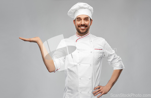 Image of happy smiling male chef holding something on hand