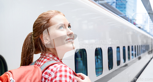 Image of smiling woman with backpack traveling over train