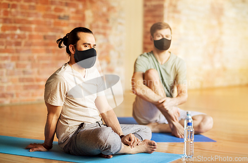 Image of men in masks resting at yoga studio