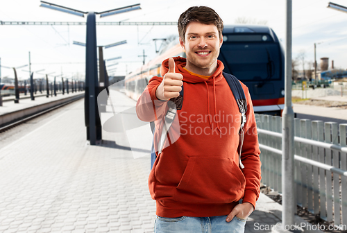 Image of man traveling by train and showing thumbs up