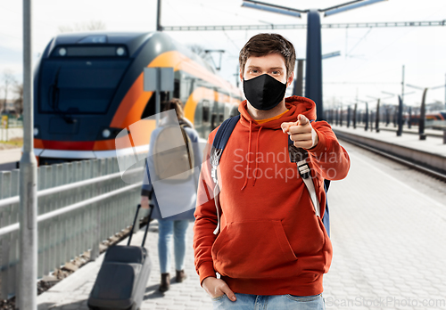 Image of man in mask with backpack traveling by train