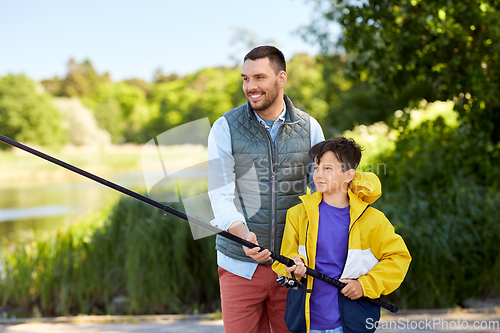 Image of happy smiling father and son fishing on river