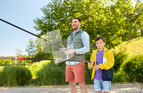 Image of happy smiling father and son fishing on river