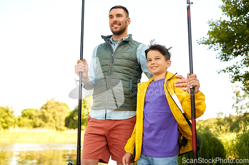 Image of happy smiling father and son fishing on river