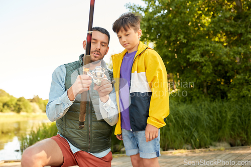 Image of happy father and son fishing on river