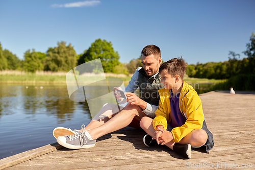 Image of father and son with smartphone on river berth