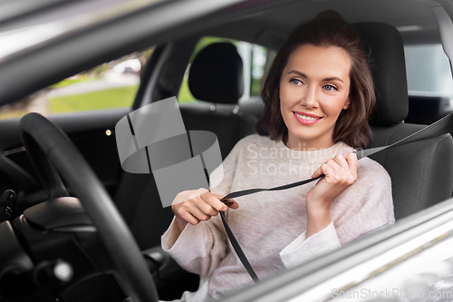 Image of woman or female car driver fastening seat belt