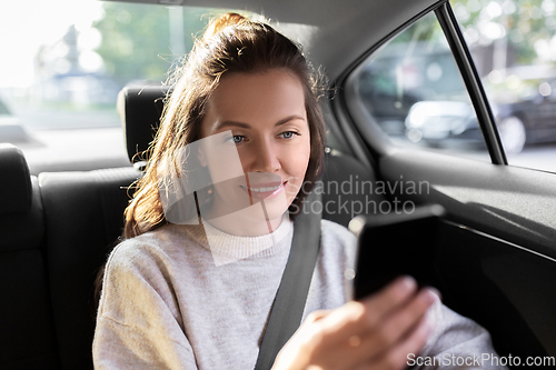 Image of smiling woman using smartphone in taxi car