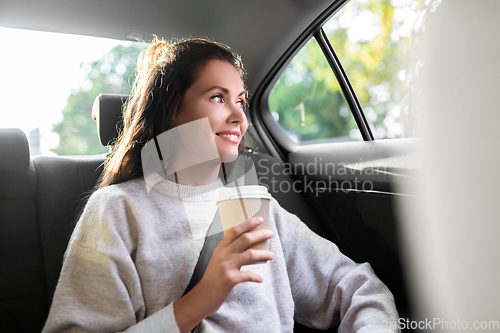 Image of woman or passenger drinking coffee in taxi car