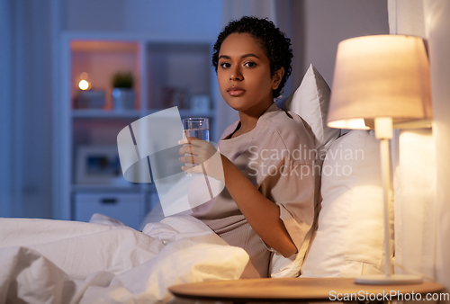 Image of african american woman drinking water at night