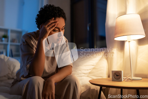 Image of stressed african woman lying in bed at night