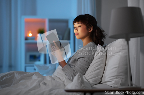 Image of asian woman with tablet pc in bed at home at night