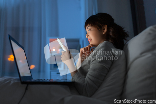 Image of asian woman with smartphone in bed at night