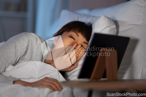 Image of asian woman with tablet pc in bed at home at night